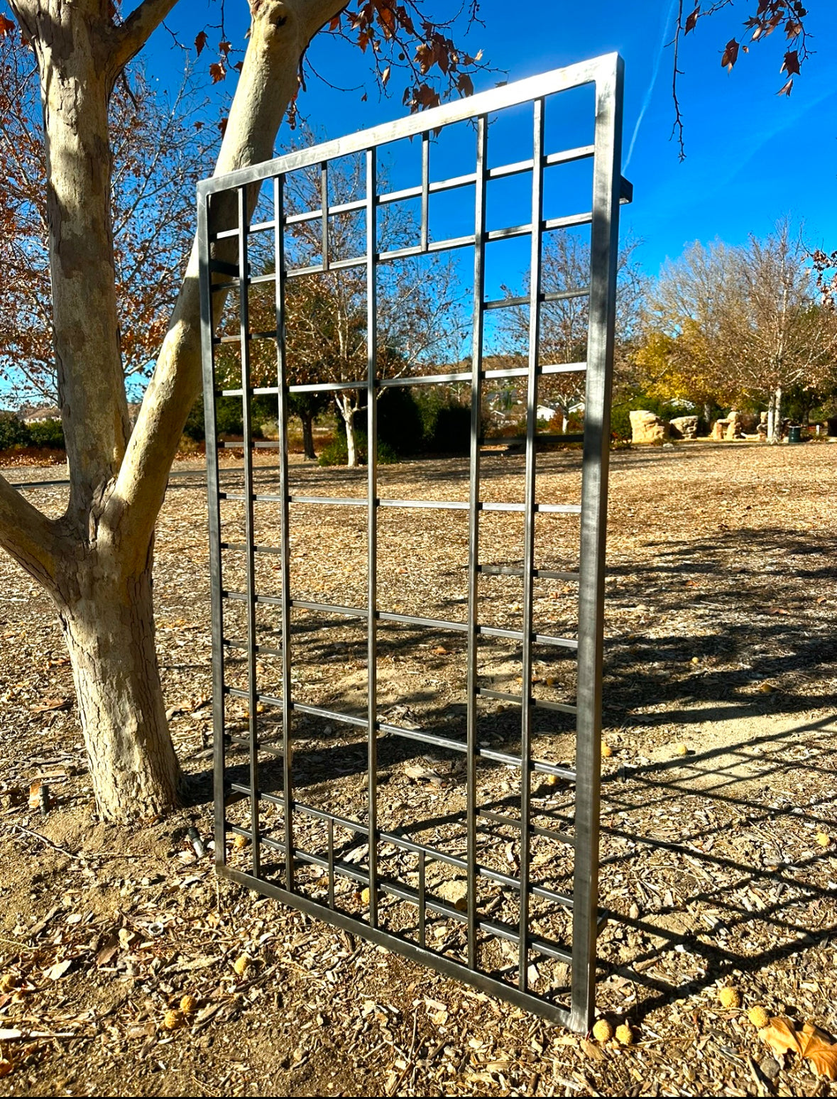 iron garden trellis in a garden setting with trees and clear sky