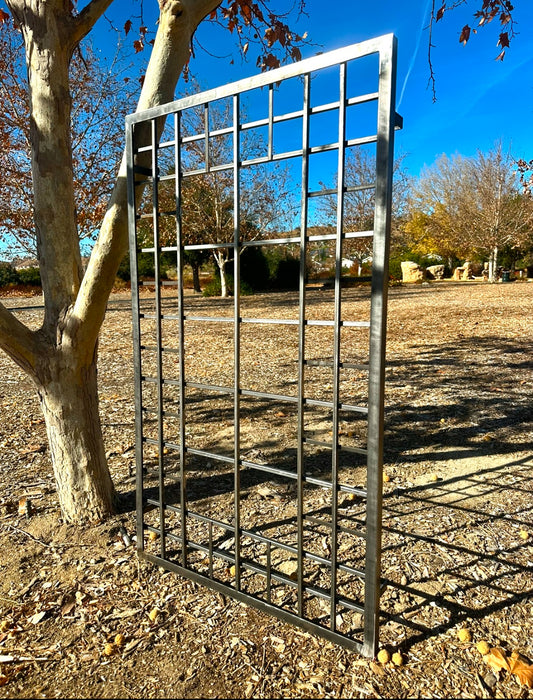 iron garden trellis in a garden setting with trees and clear sky