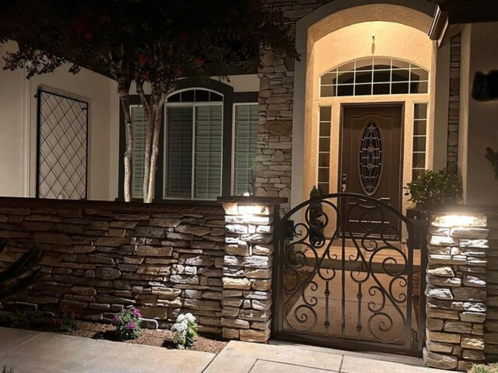 Elegant entrance to a house with a stone wall and decorative gate.